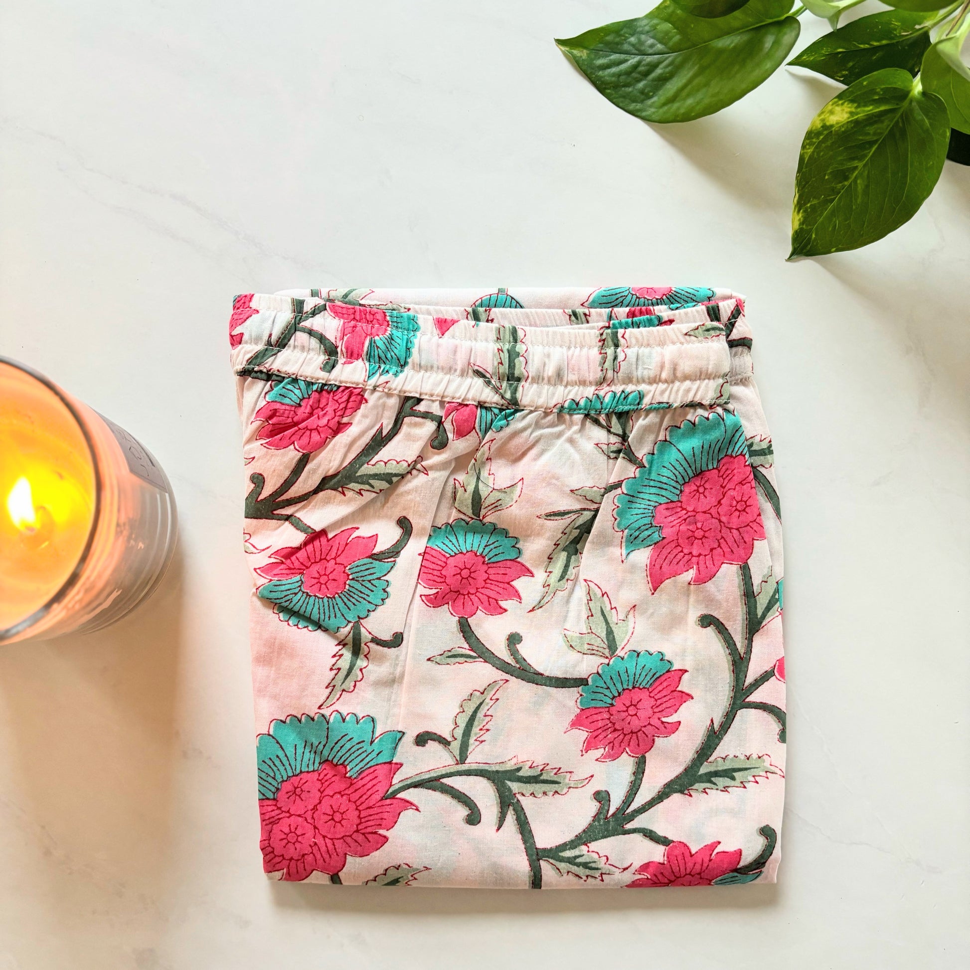 Soft and breathable cotton pajama pants for women with pink and green floral print on white, featuring pockets and an elastic waistband.