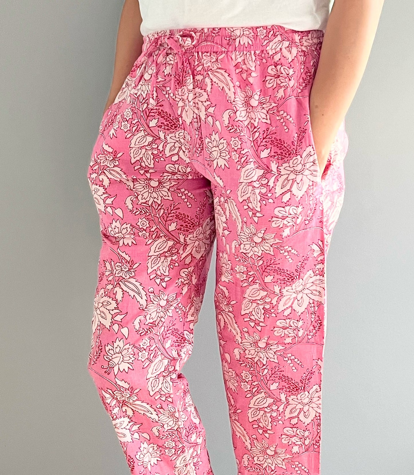 Floral-patterned 100% cotton pajama pants in soft pink, designed with pockets and an elastic waistband, perfect for cozy nights and casual days at home.