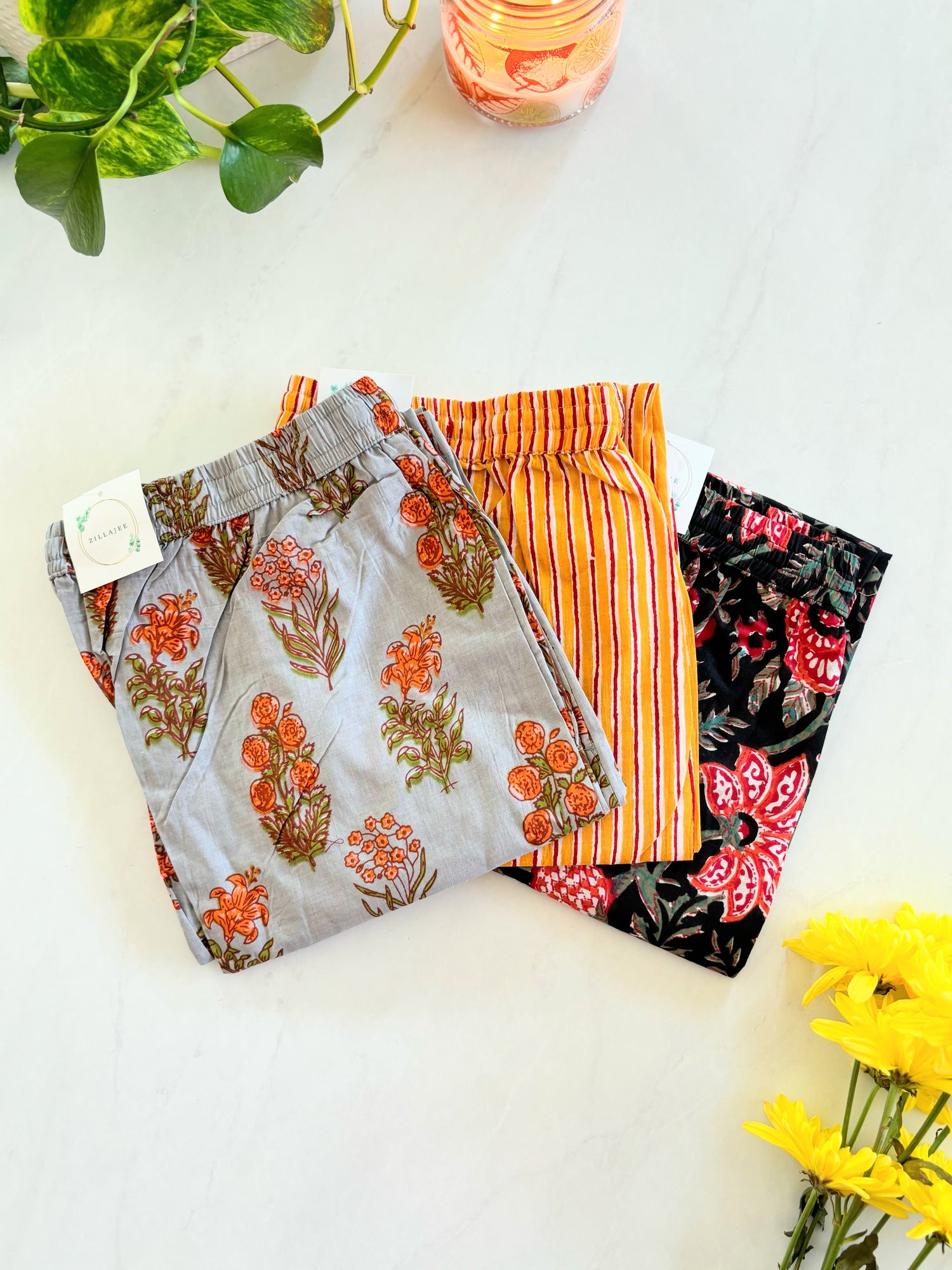 Relaxed fit 3-pack of cotton pajama pants for women with pockets, elastic waistband, and drawstring in vibrant gray, orange, and red prints. Soft, breathable sleep pants for ultimate comfort.