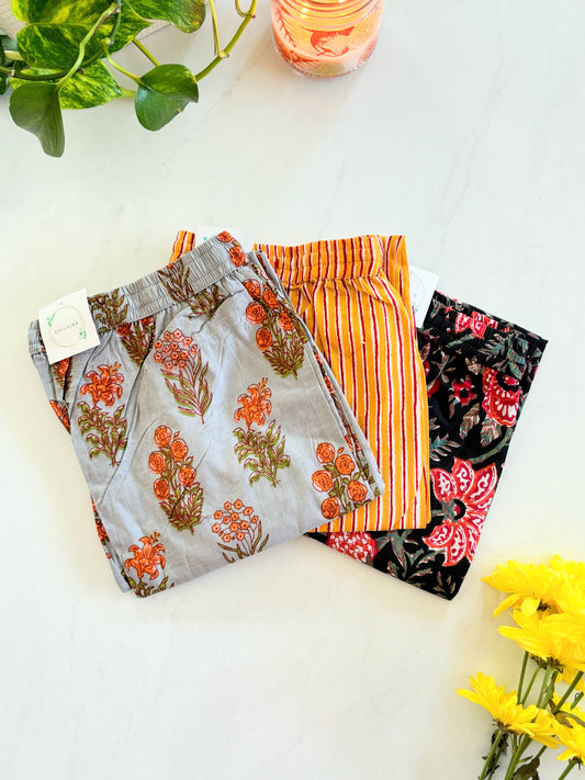 Relaxed fit 3-pack of cotton pajama pants for women with pockets, elastic waistband, and drawstring in vibrant gray, orange, and red prints. Soft, breathable sleep pants for ultimate comfort.