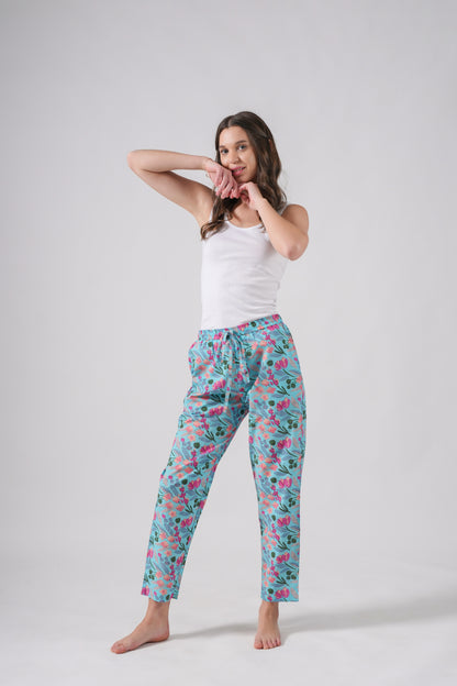 Lightweight and relaxed fit pajama bottoms with vibrant pink floral accents on soft blue, featuring drawstring waist and functional pockets — versatile lounge & sleepwear.