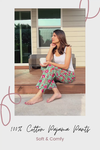 Soft and breathable 100% cotton pajama pants for women, with pink and white flowers on a light green background, elastic waist, and practical pockets