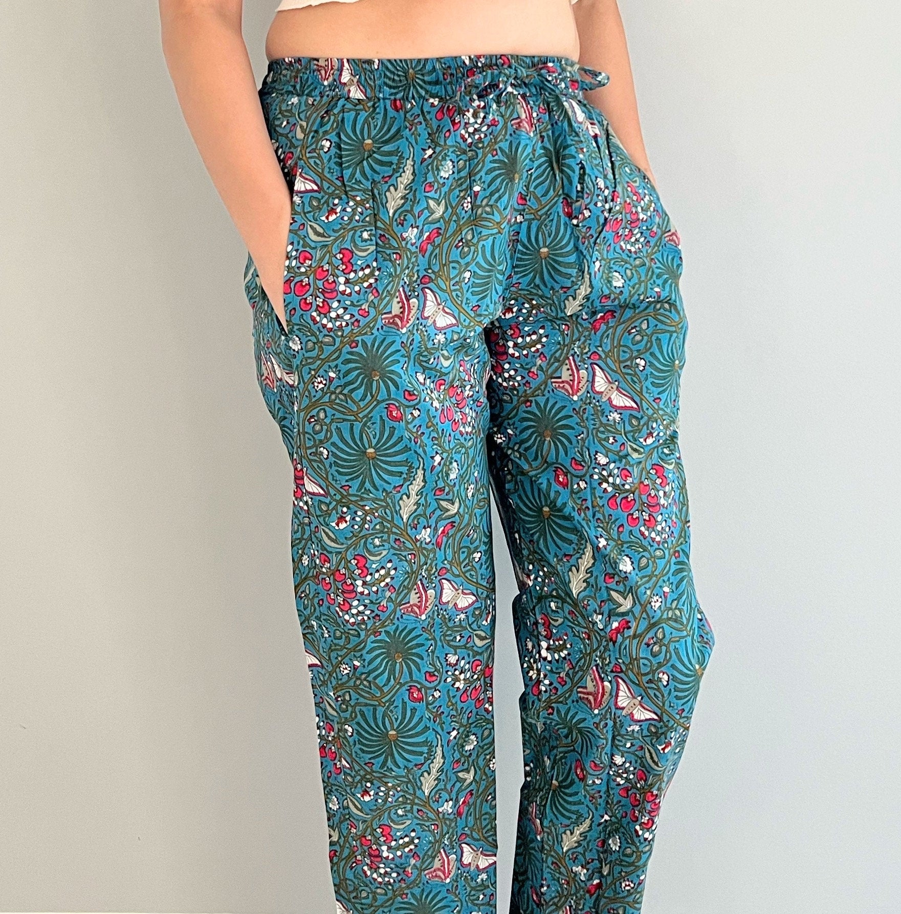 Floral and butterfly print cotton pajama pants for women in dark blue. These comfortable pants have an elastic waist, pockets, and are ideal for lounging and relaxing.
