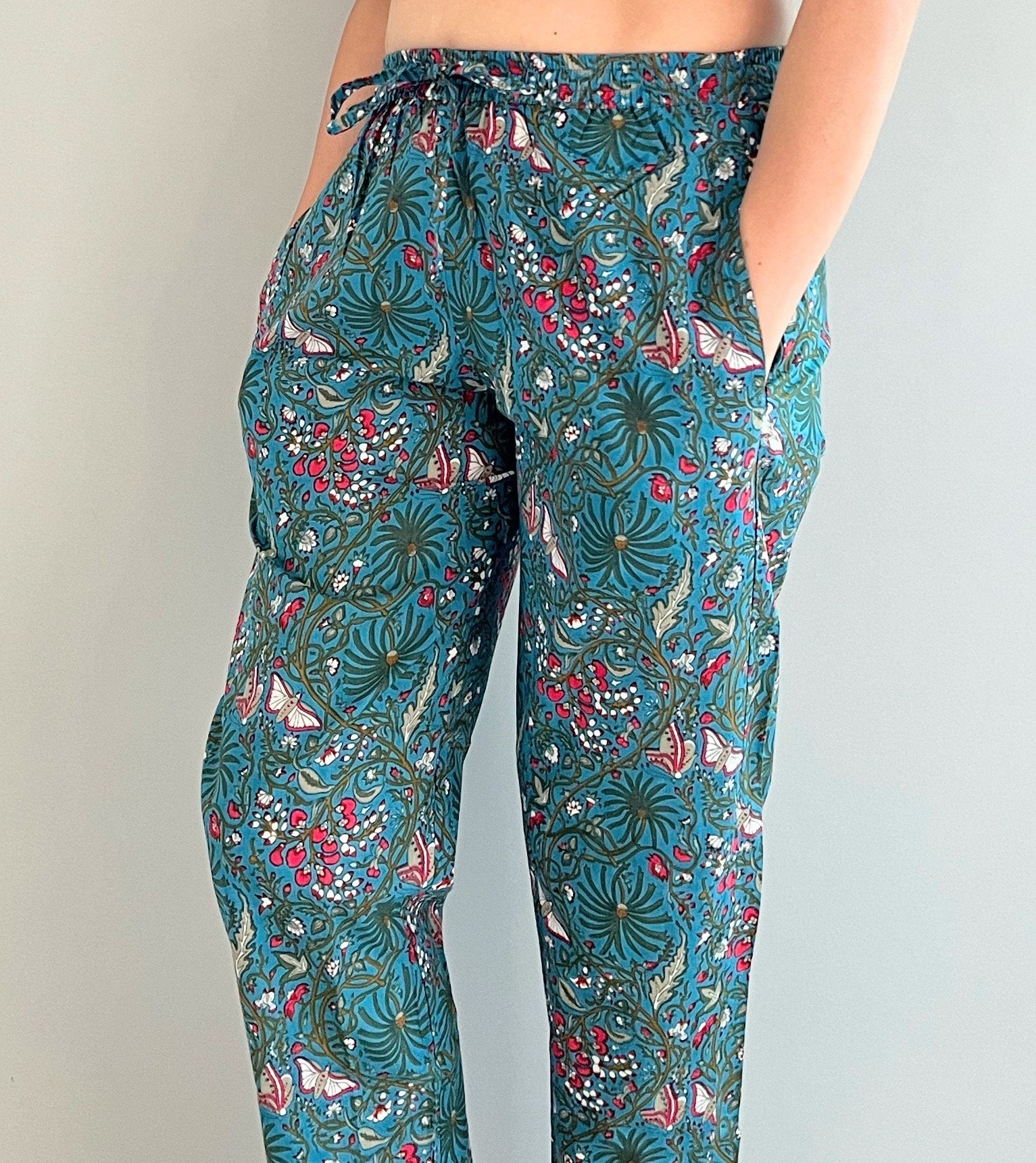 Soft 100% cotton pajama pants for women with a floral and butterfly print on a dark blue background. Designed with pockets and an elastic waistband, these pants are perfect for lounging.
